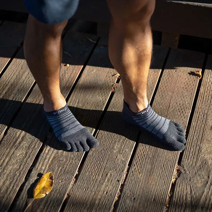 Person wearing Injinji Ultra Run Light Weight Wool No Show Mens Slate toe-separated socks on a wooden floor