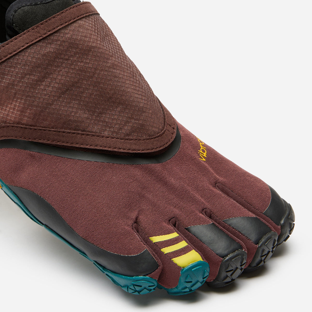 A close-up of a minimalist five-toe shoe,  model, featuring a textured brown and burgundy upper, black toe caps and sole, with bright yellow three-stripe accents and teal outsole details, set against a clean light gray background.